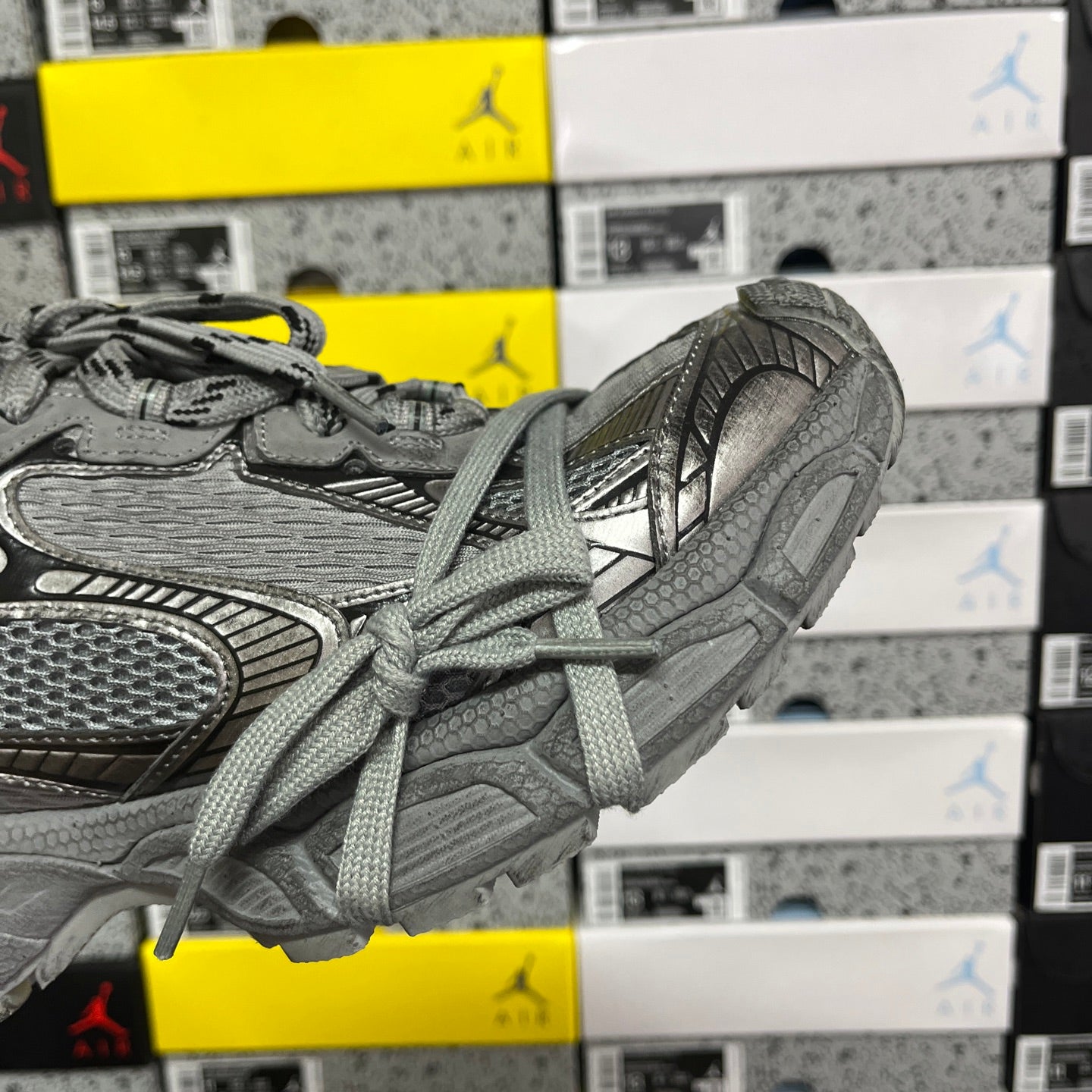 Gray sneaker side profile with lace-up closure and layered textured panels