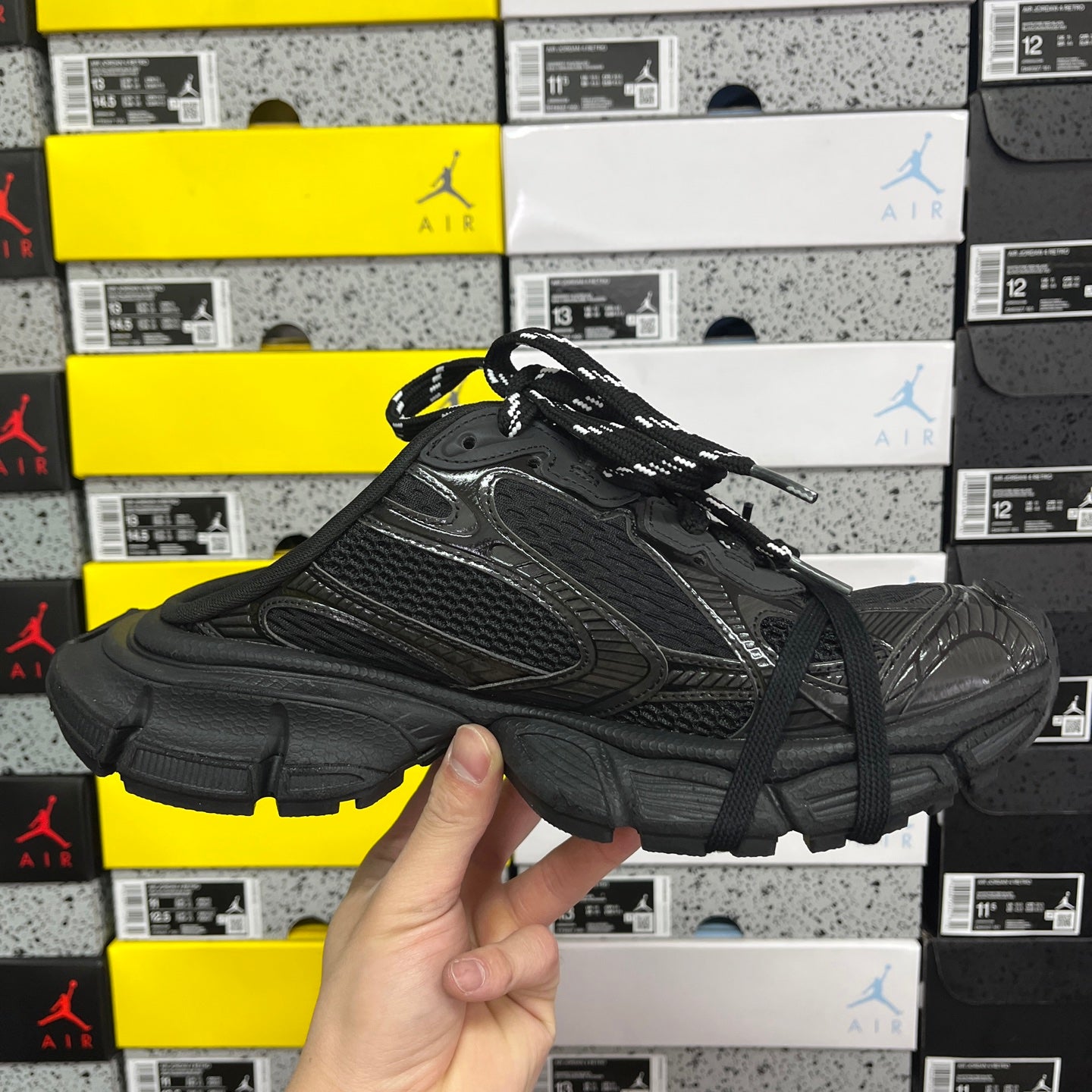 Black lace-up sneakers with textured overlays and thick sole with side tread