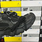 Black sneakers showing side profile, textured upper, and padded heel