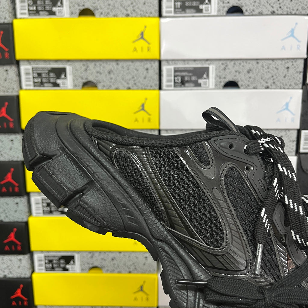 Black sneakers from the side with mesh panels, curved toe cap, and lace-up closure