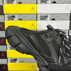 Black sneakers from the side with mesh panels, curved toe cap, and lace-up closure