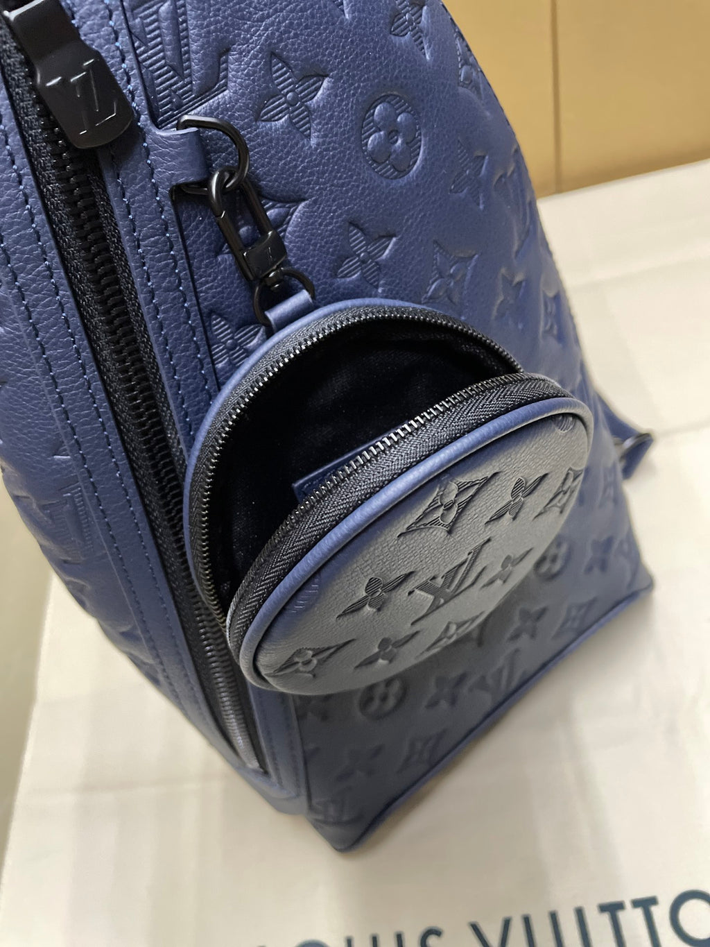 Dark blue monogram sling bag detail with zipper and interior pocket opening