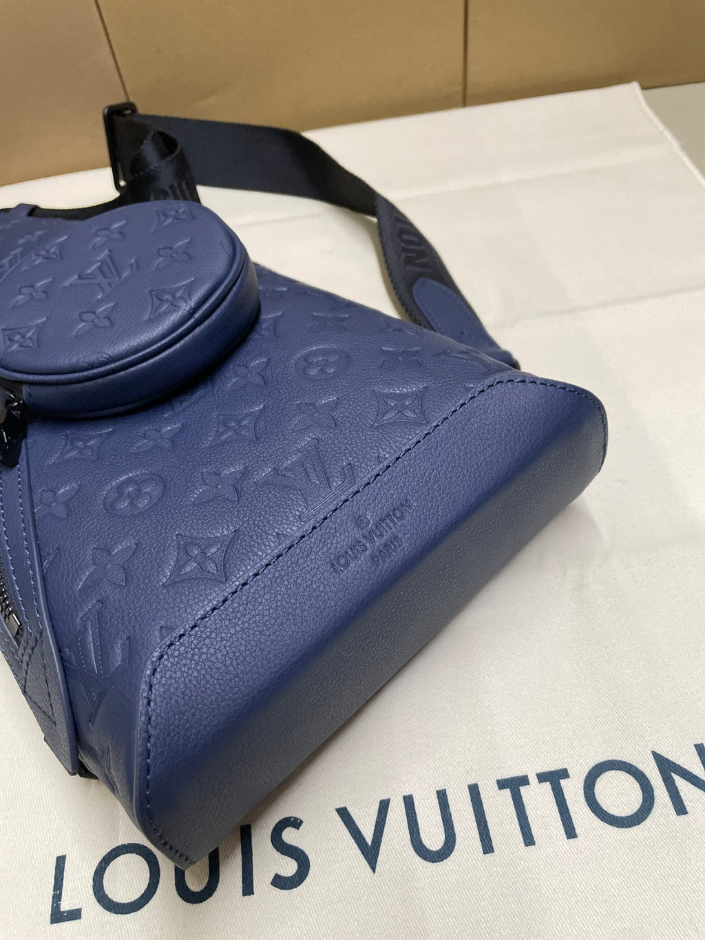 Blue monogram bag close-up with curved handle and stitched leather trim