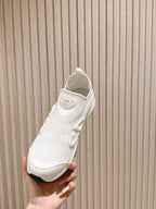 White slip-on sneakers close-up, front and side view with Dior logo badge