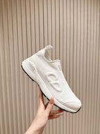 White slip-on sneaker held in hand, side profile with Dior logo detail