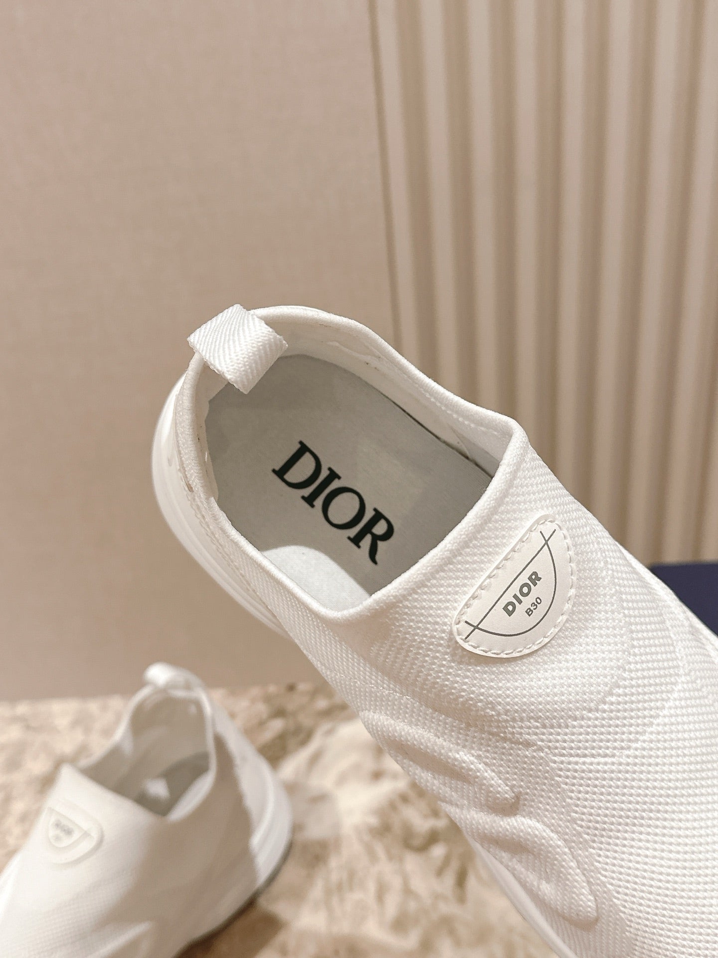 White slip-on sneaker close-up, inner lining with DIOR text on the tongue