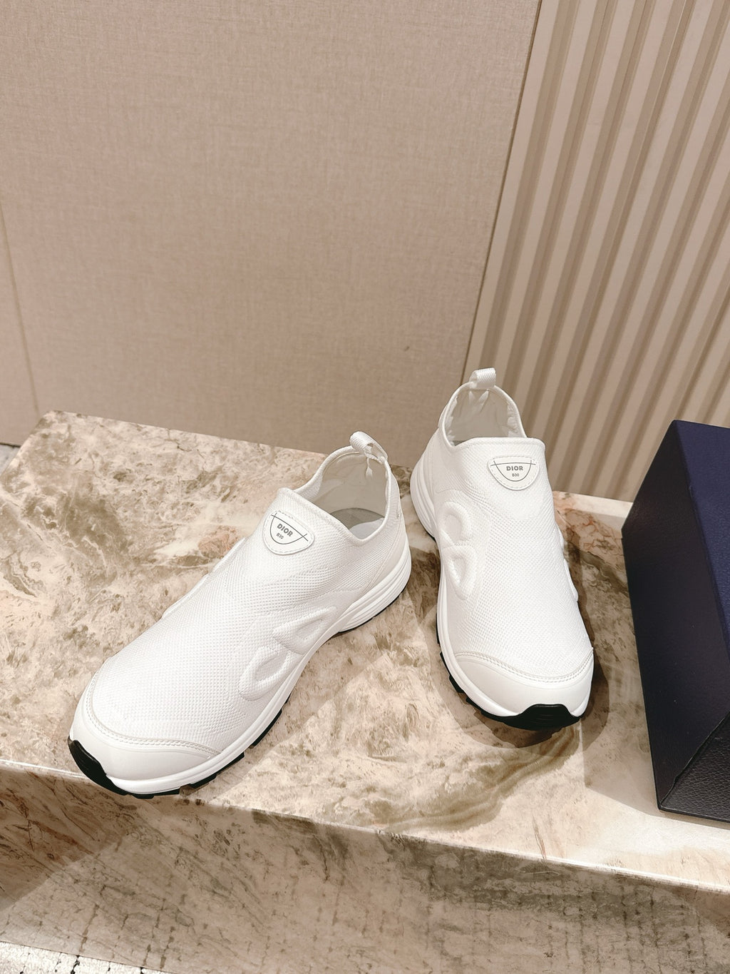 White slip-on sneakers, angled pair view with embroidered Dior logo on the sides
