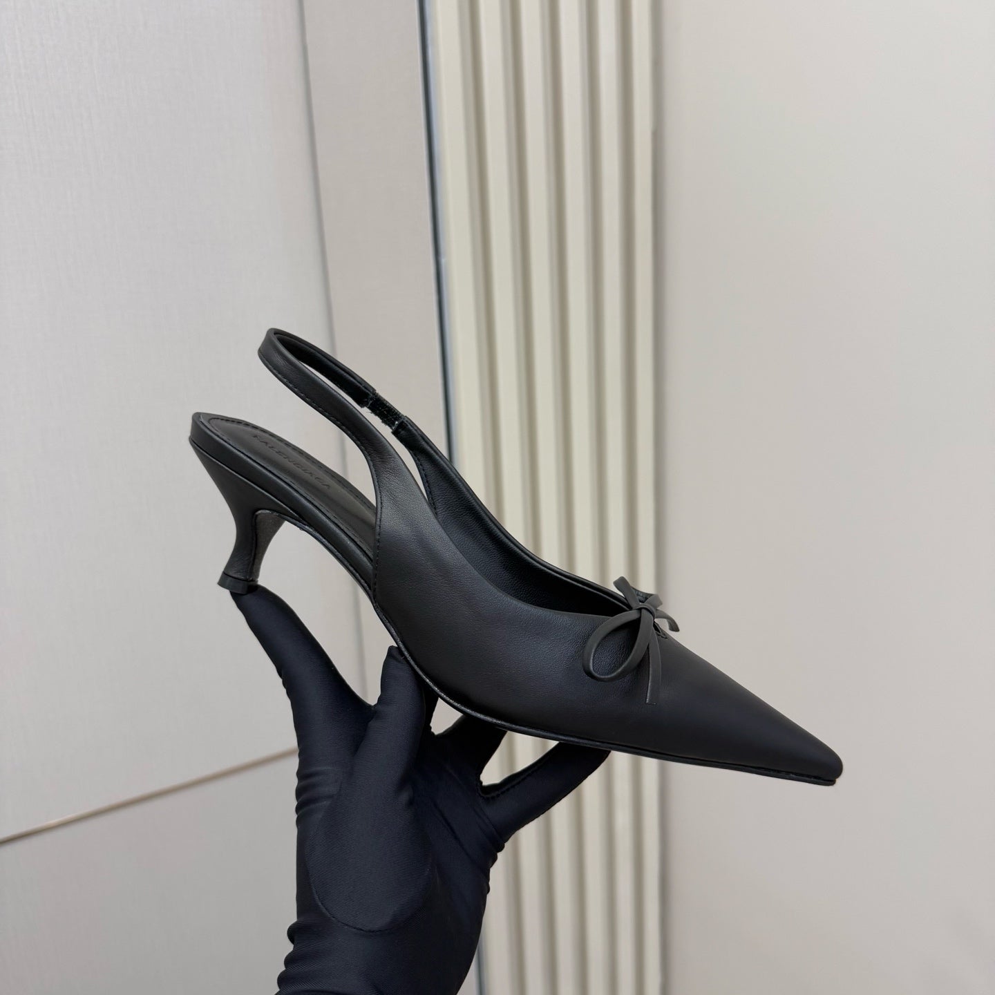 Black pointed-toe slingback heels with bow at vamp and stiletto heel