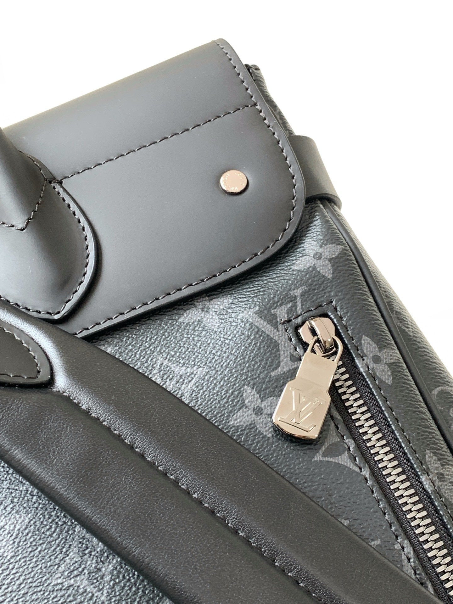 Louis Vuitton bag detail: snap pocket, zipper with metal pull, and black leather trim