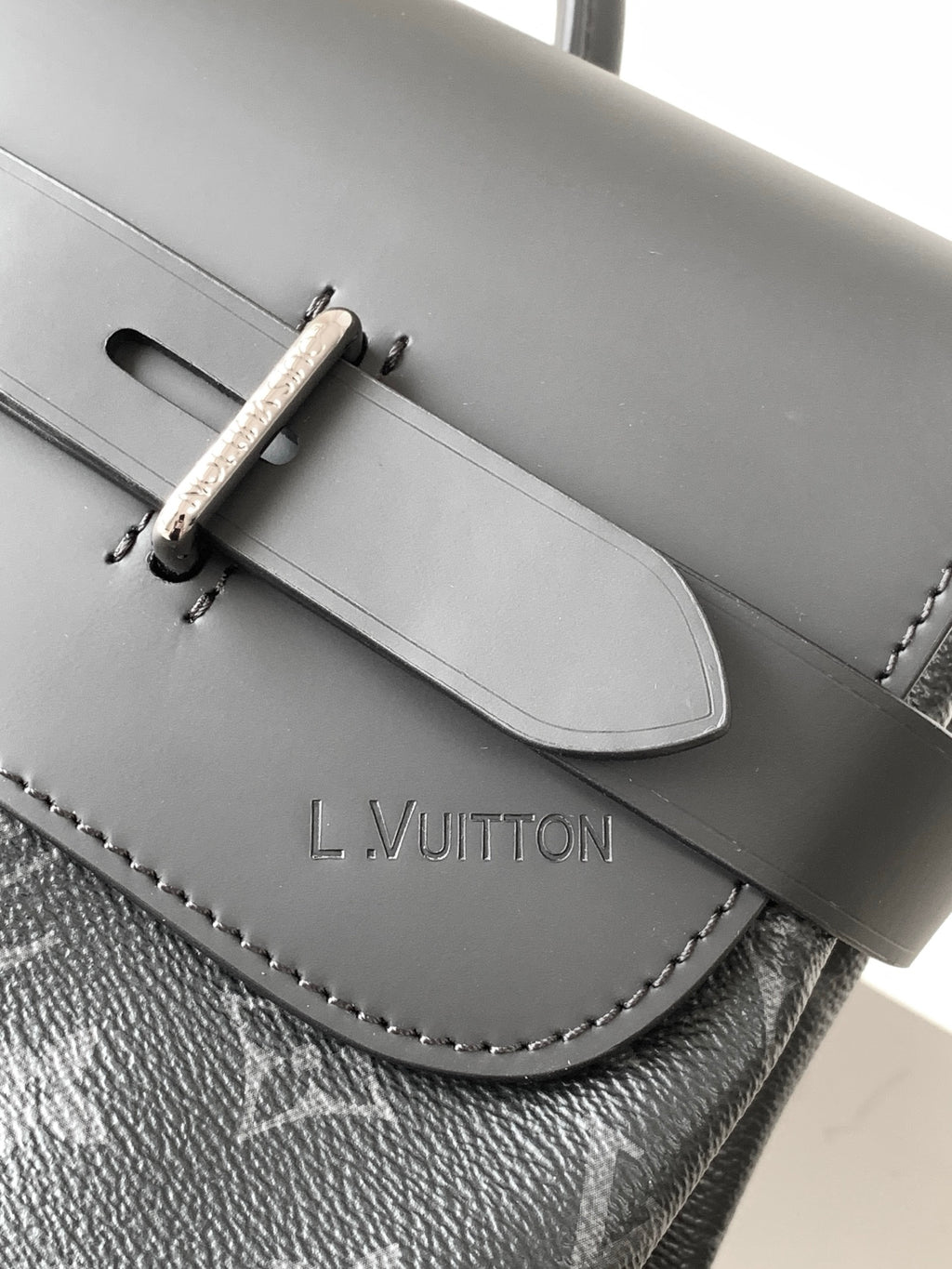 Louis Vuitton bag front flap with snap closure, engraved L.VUITTON, and stitched monogram trim