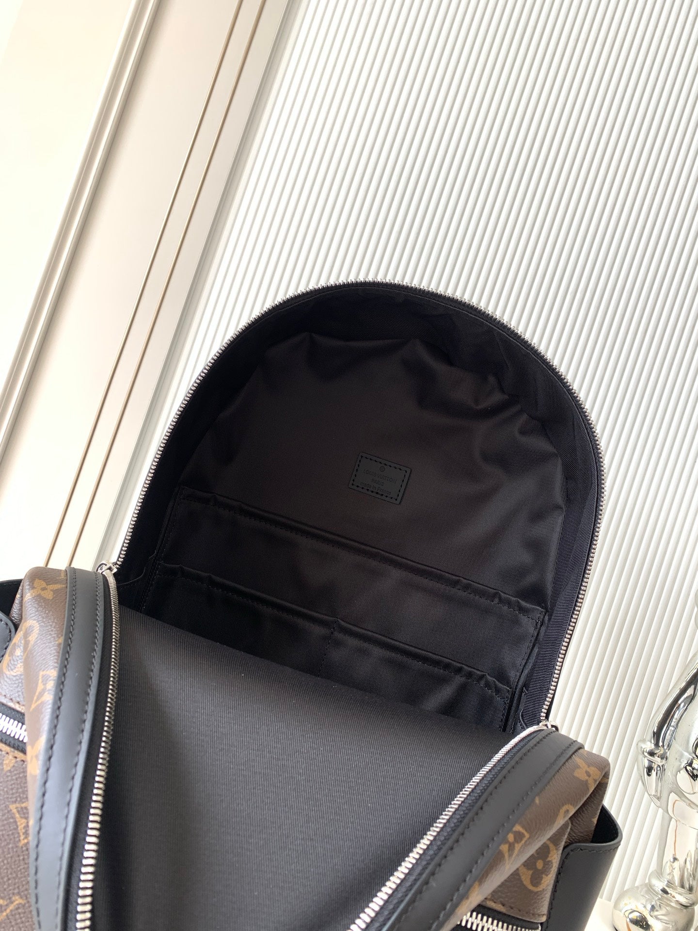 Louis Vuitton monogram backpack open showing black fabric lining and inner pocket