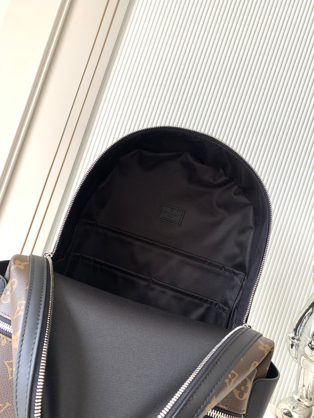 Monogram canvas backpack open view showing dark interior lining and zipper top