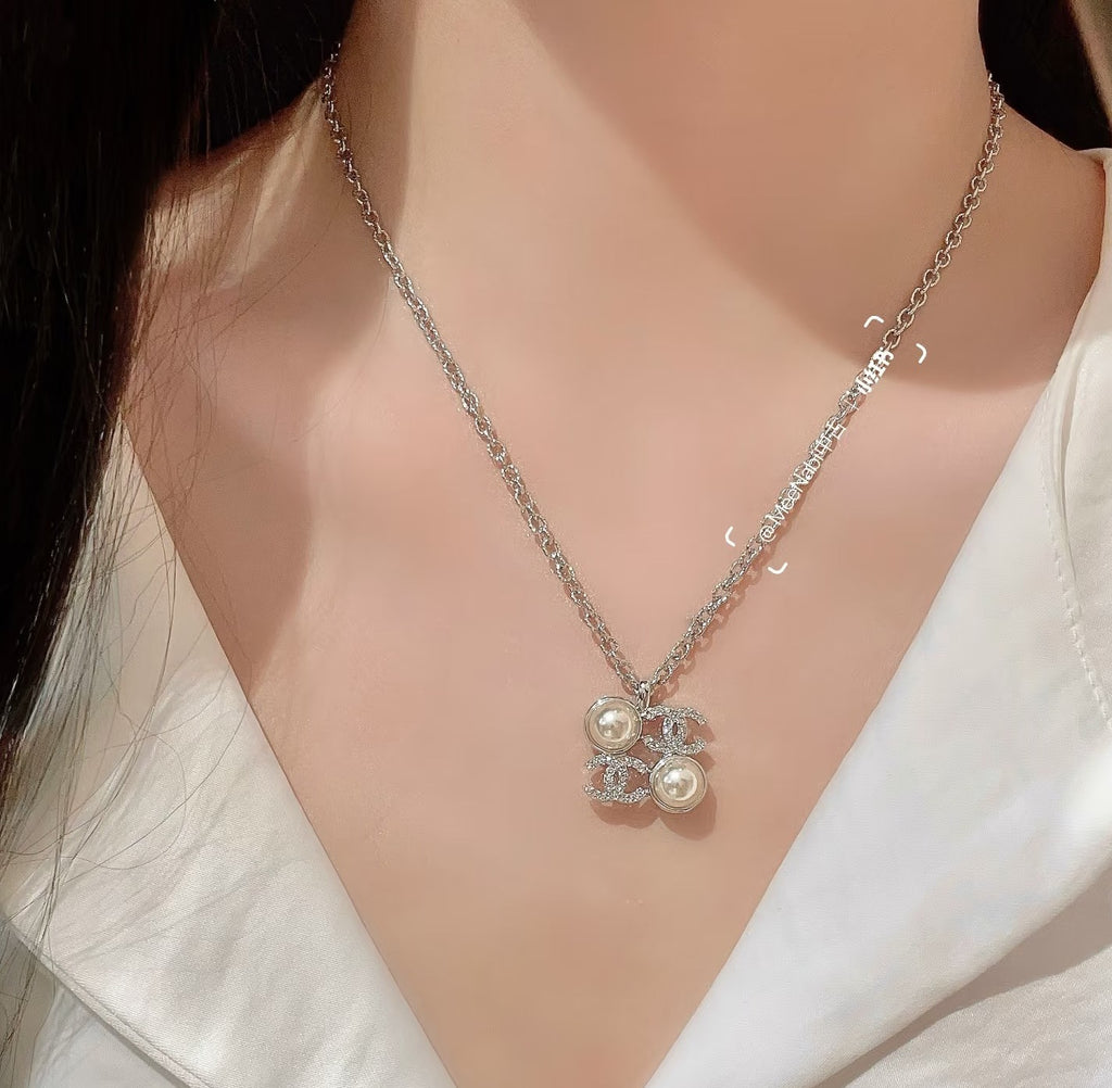 Chanel silver-tone pendant necklace with pearl flower charm, close-up on neckline