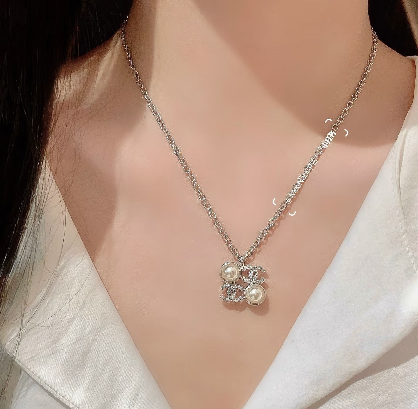 Chanel silver-tone pendant necklace with pearl flower charm, close-up on neckline