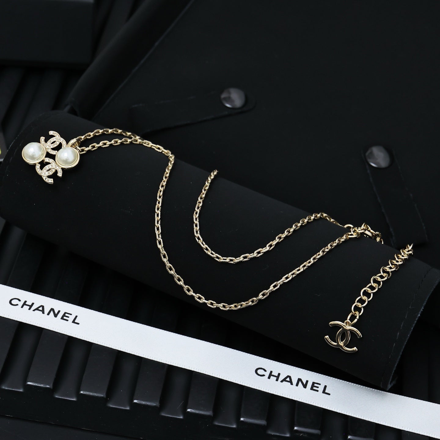 Chanel gold-tone layered necklace with pearl bow charm and logo detail