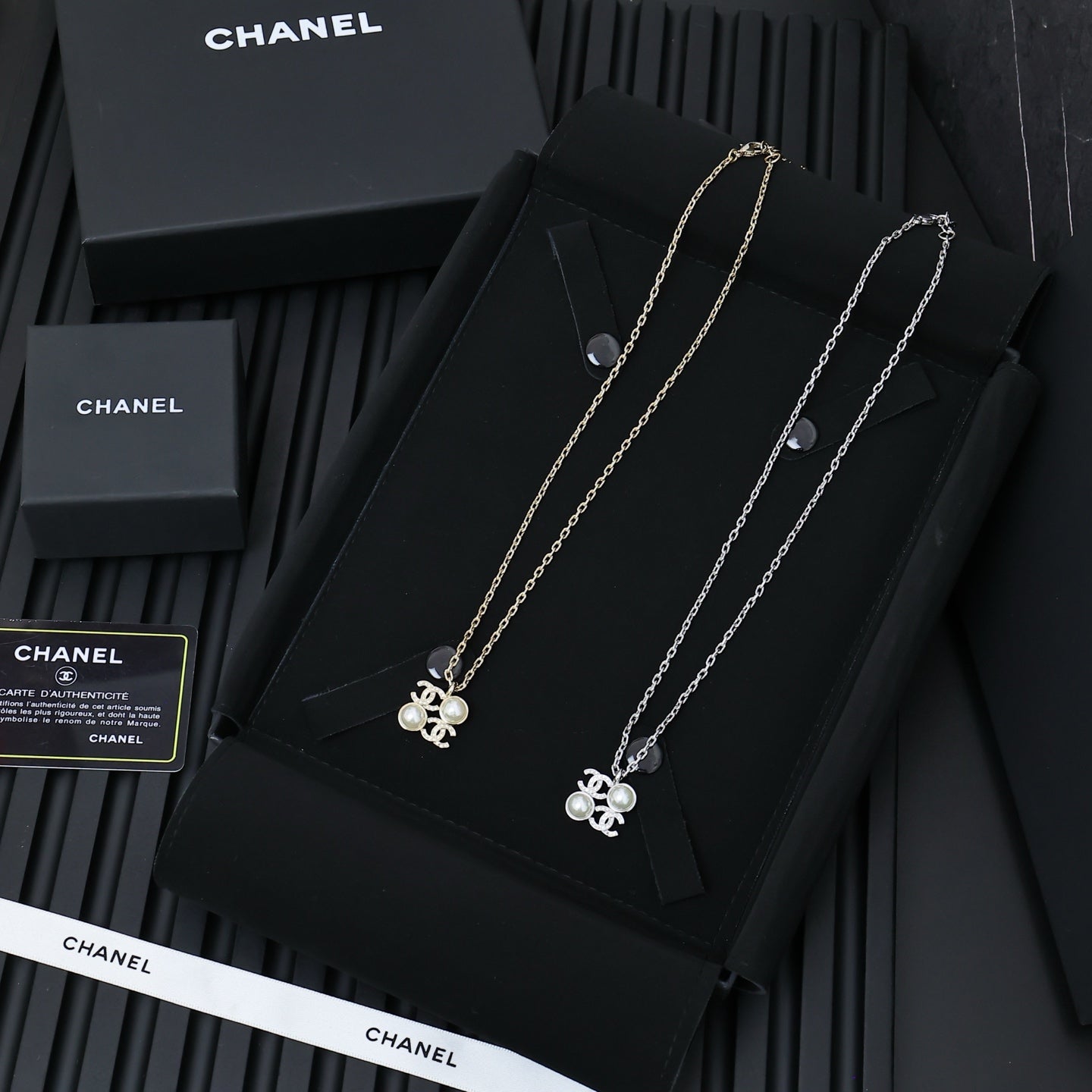 Chanel silver-tone pendant necklaces on a display card, multiple chain lengths