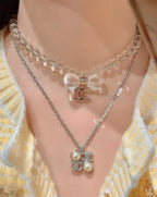 Chanel silver-tone layered pendant necklace with bow and flower charms, on neckline