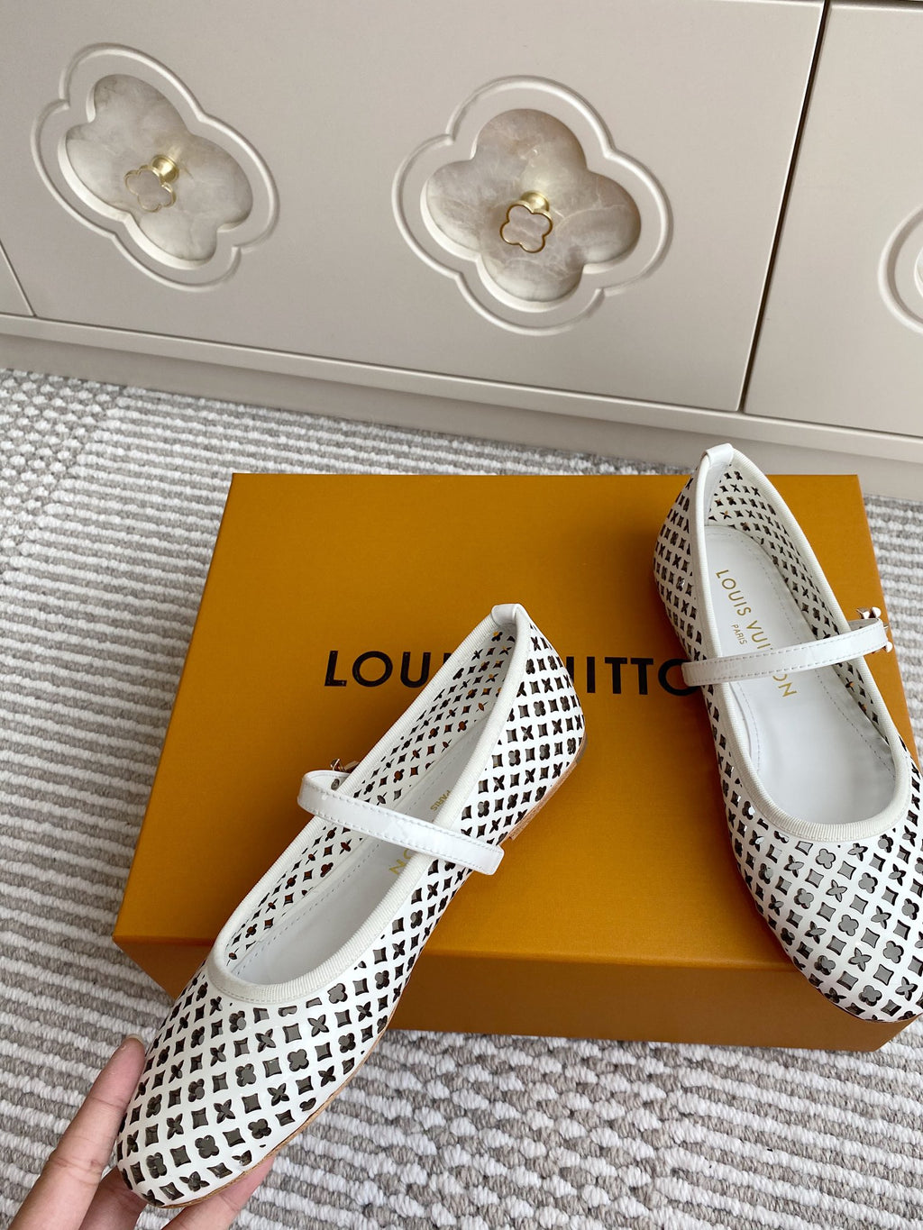 Louis Vuitton logo-pattern flats with white strap, one shoe close-up on box