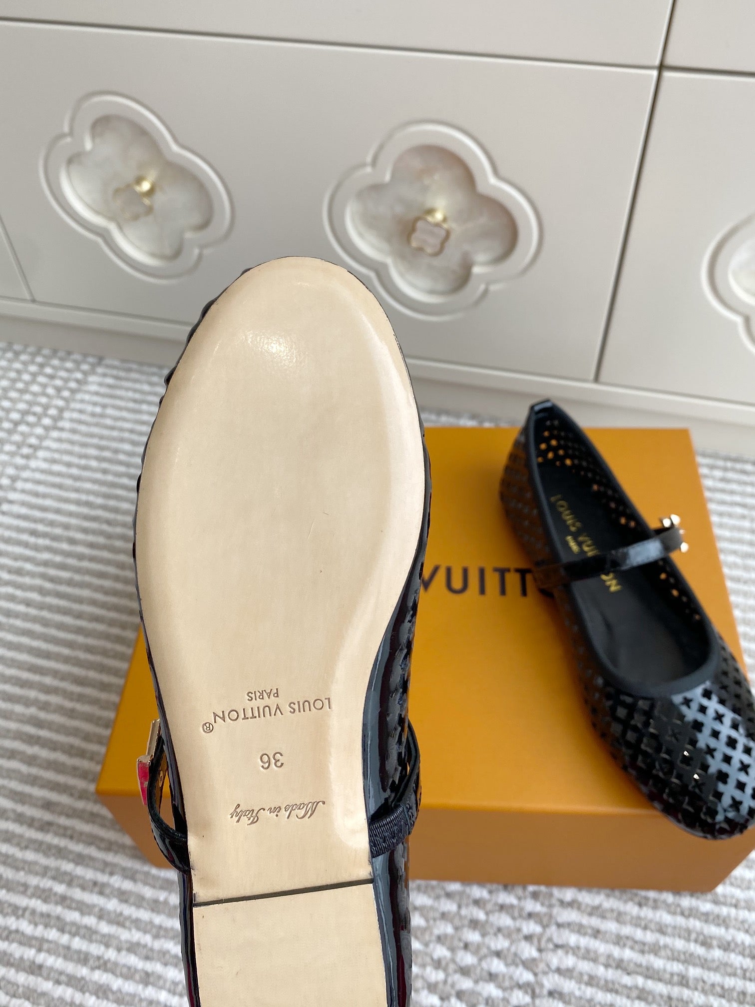 Black patterned flat ballerina shoe with buckle strap, outsole and insole view