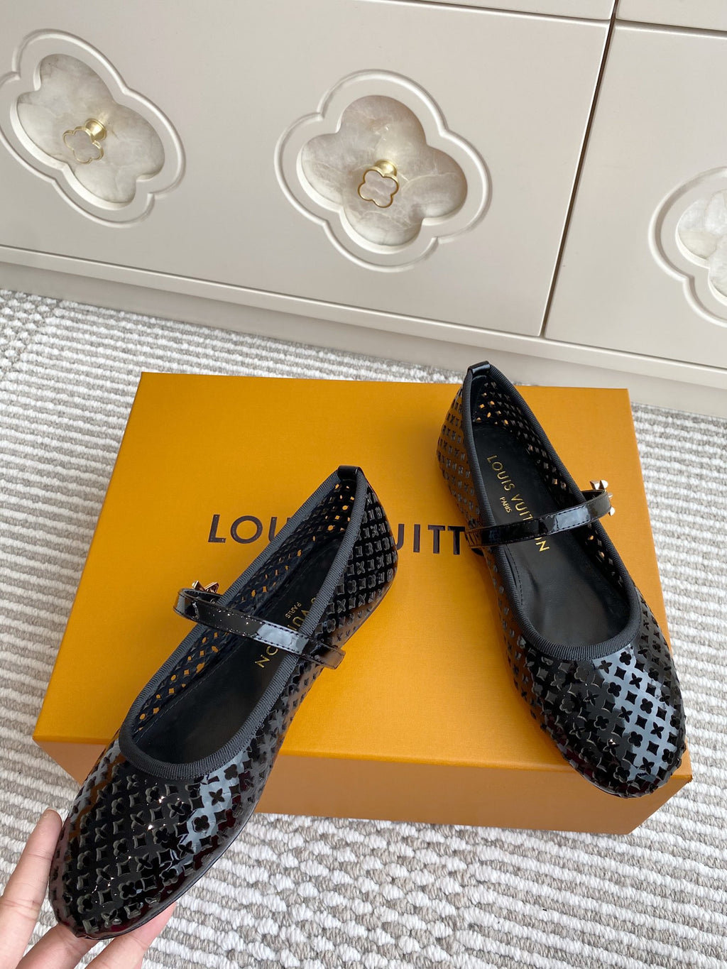 Pair of black patterned flat ballerina shoes with buckle straps, angled view