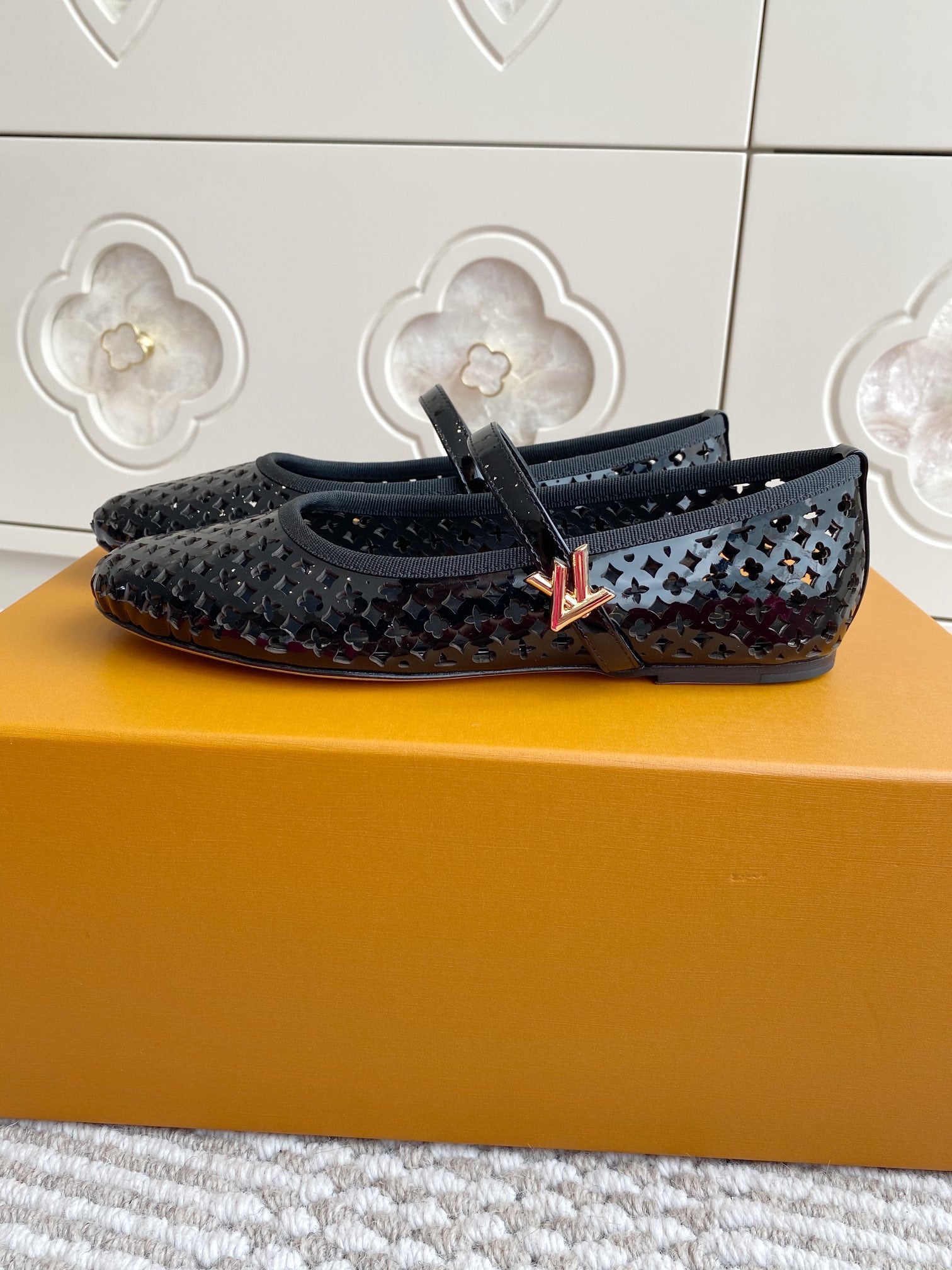 Black and white patterned flat ballerina shoe with buckle strap, side view