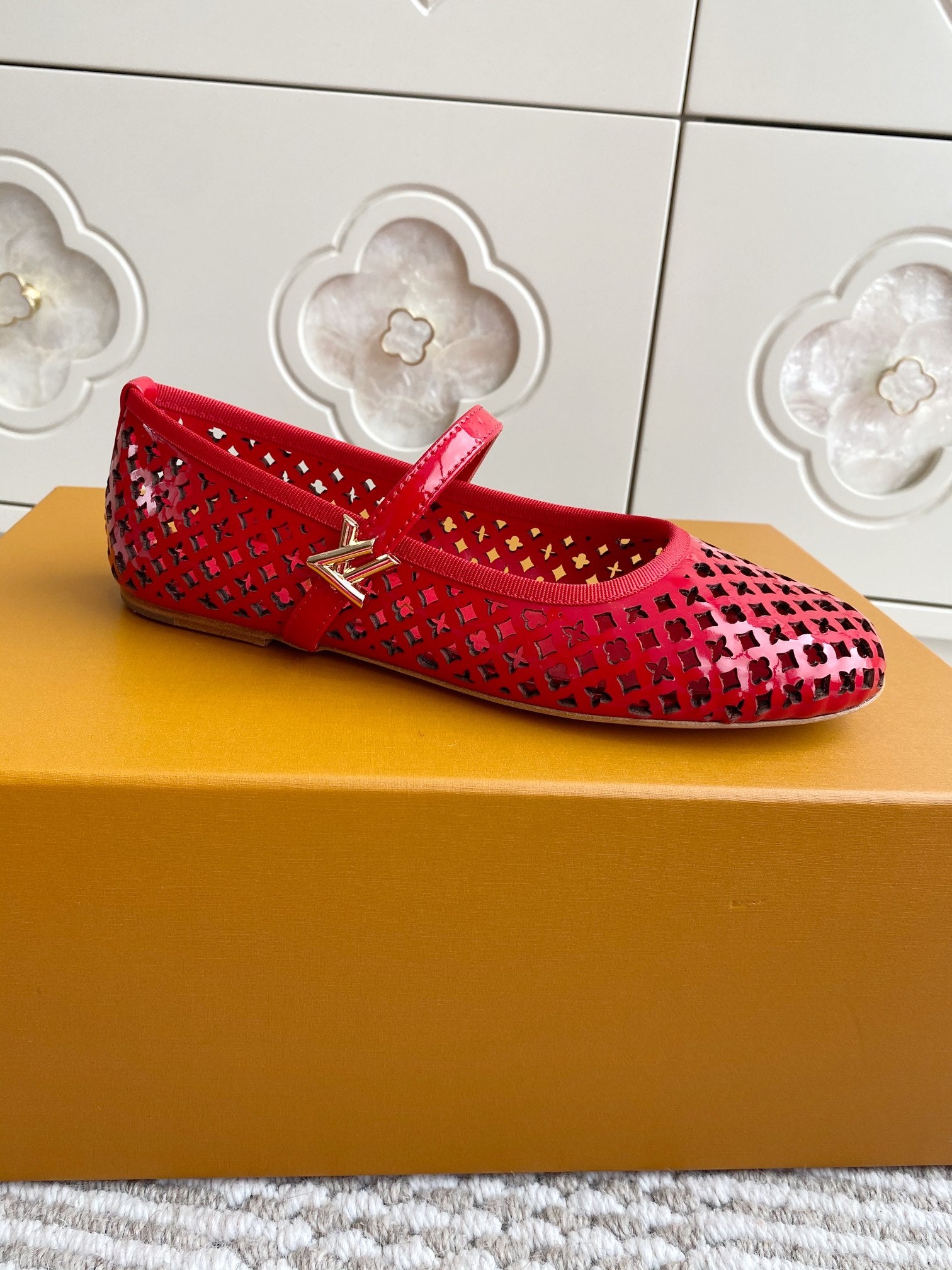 Women's Louis Vuitton red flats with cutout lattice design and gold buckle strap