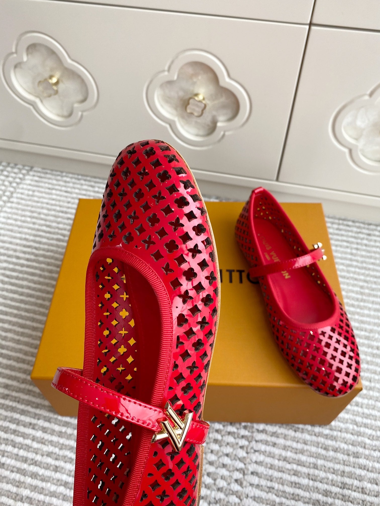 Women's Louis Vuitton red flats with cutout pattern, sling strap, and gold buckle