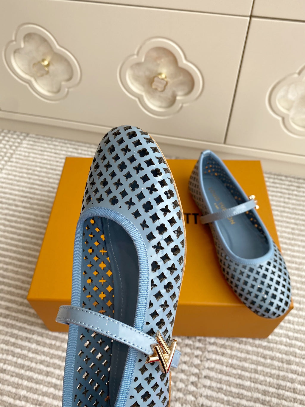 Side view of light blue perforated flats with ankle strap and gold-tone emblem