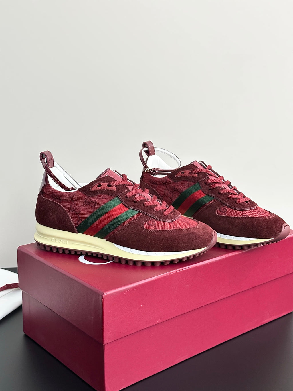 Two dark red sneakers with green stripes, lace-up front, and cream rubber sole