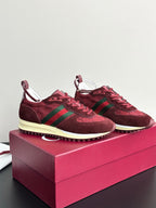 Two dark red sneakers with green stripes, lace-up front, and cream rubber sole