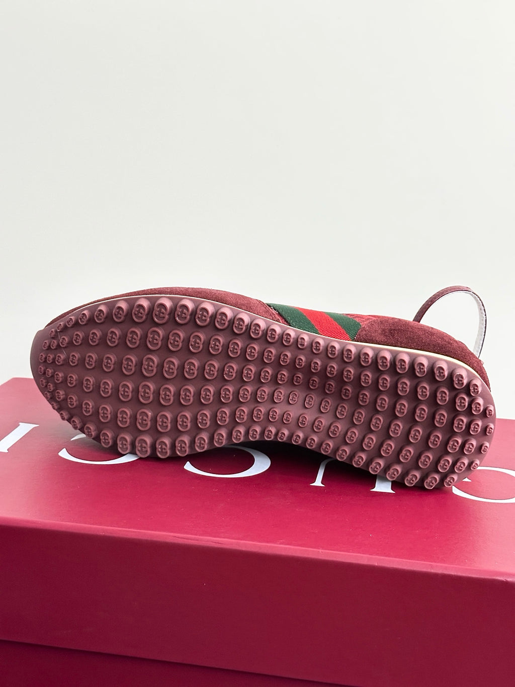 Shoe outsole tread with dark red rubber and green stripe near the toe