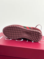 Shoe outsole tread with dark red rubber and green stripe near the toe