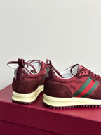 Back view of dark red lace-up sneakers with green stripe and cream midsole