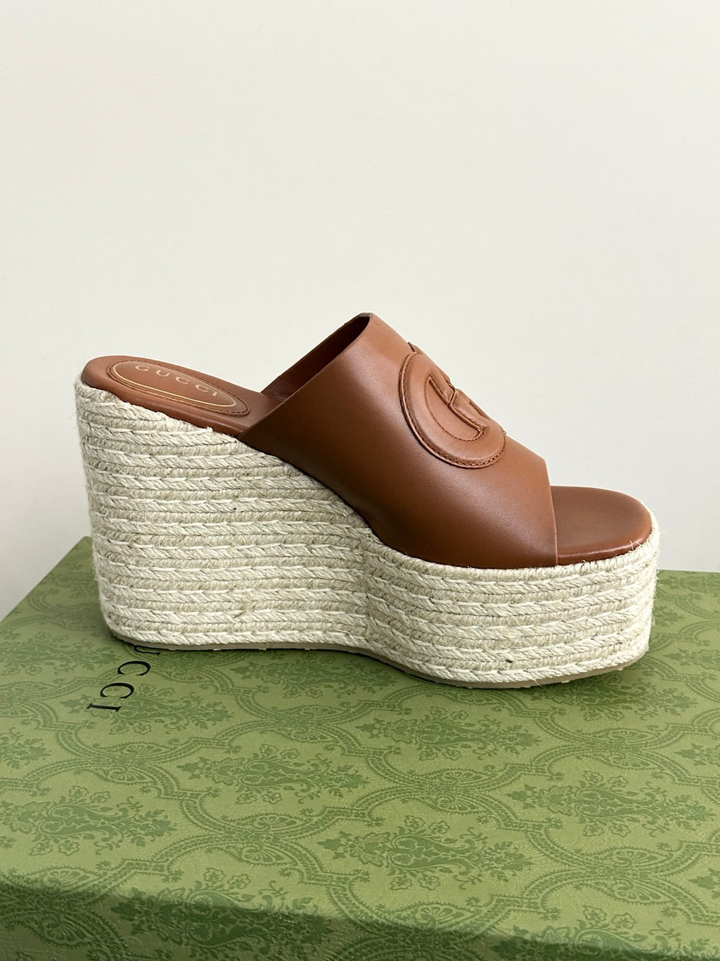 Gucci brown leather open-toe slide sandal on espadrille wedge, side view with GG detail