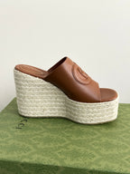 Gucci brown leather open-toe slide sandal on espadrille wedge, side view with GG detail