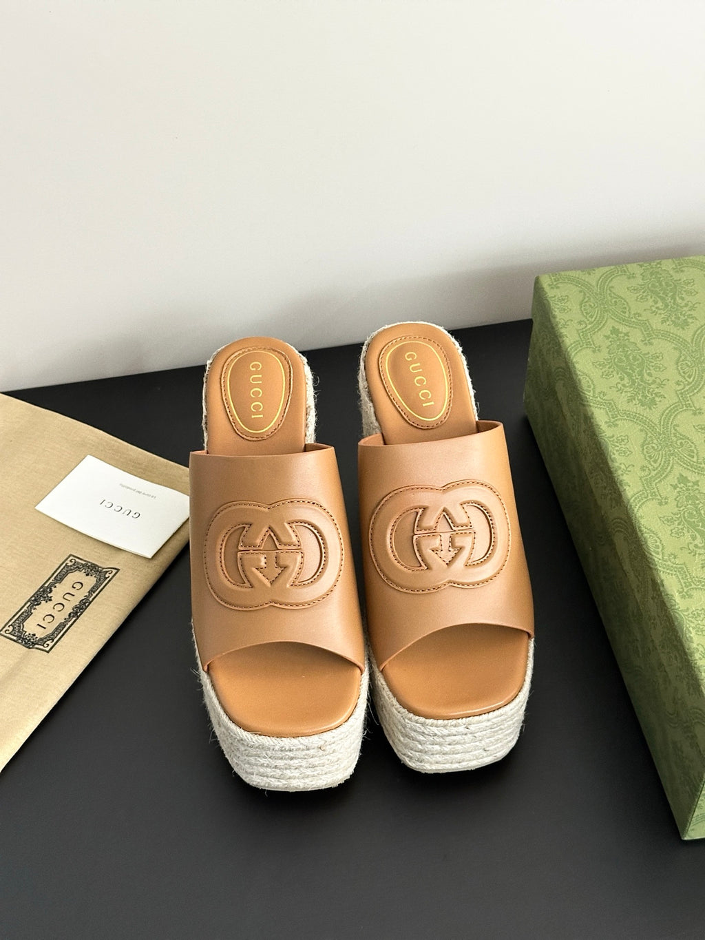 Gucci ladies tan leather slide sandals with logo emblem and white espadrille wedge sole.
