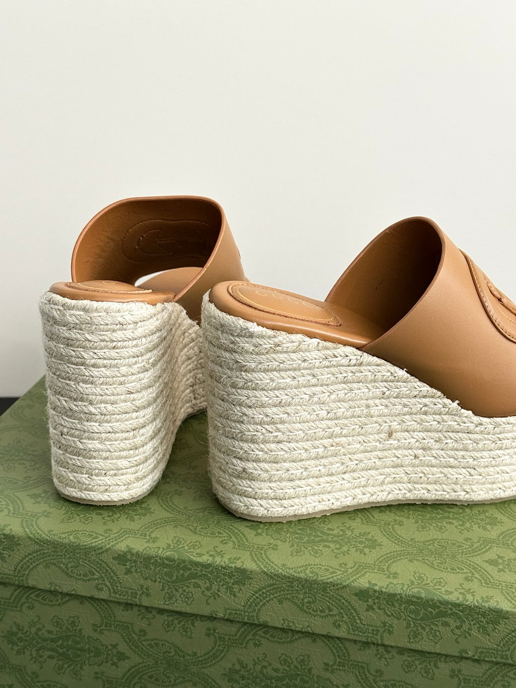 Gucci tan wedge slide sandals with open toe and white textured platform, angled view.
