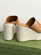Gucci tan wedge slide sandals with open toe and white textured platform, angled view.