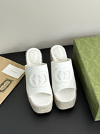 White Gucci platform slides with embossed logo on wide straps and espadrille wedge sole