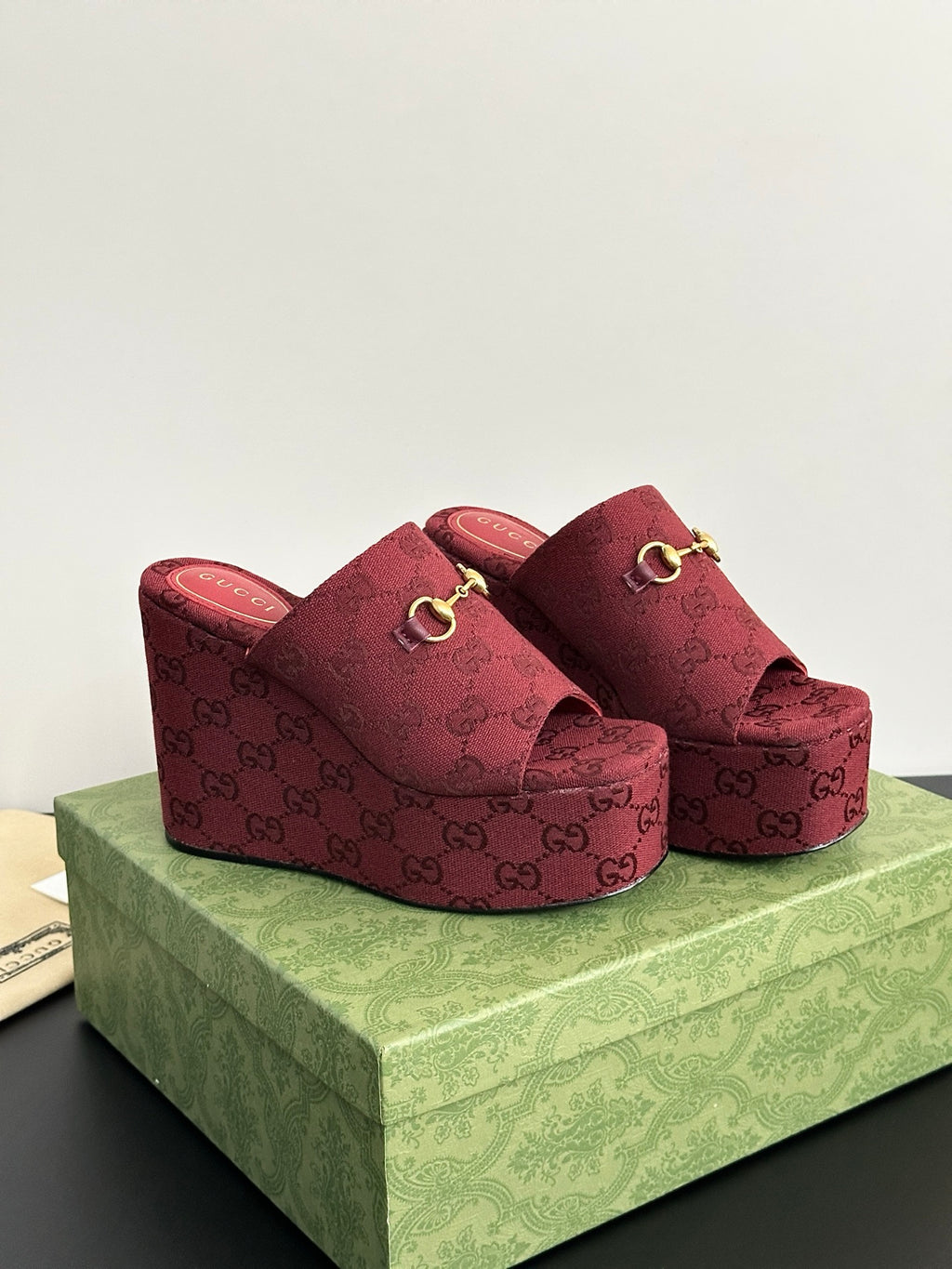 Burgundy Gucci platform mules with GG monogram upper and gold-toned buckle strap