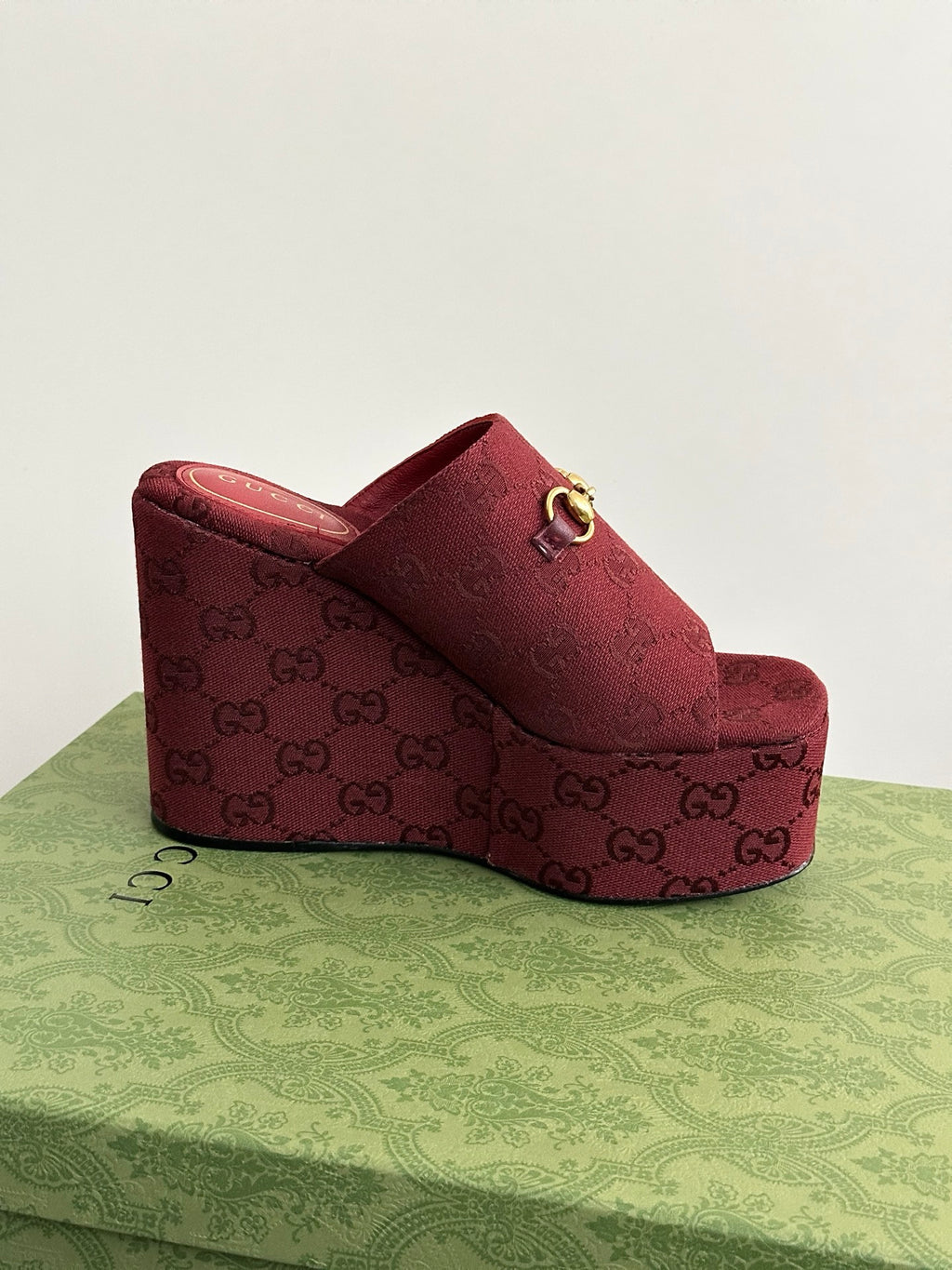 Burgundy Gucci wedge mules with open toe and GG monogram pattern on footbed
