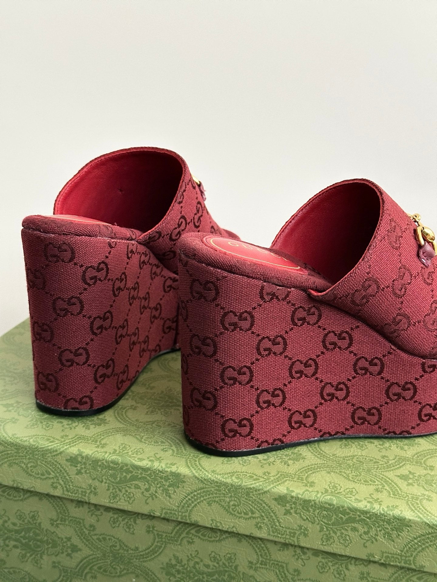 Burgundy Gucci wedge mules, side view, with GG monogram upper and gold buckle