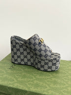 Gucci GG-print platform slide sandal with gold-tone buckle detail, side view.