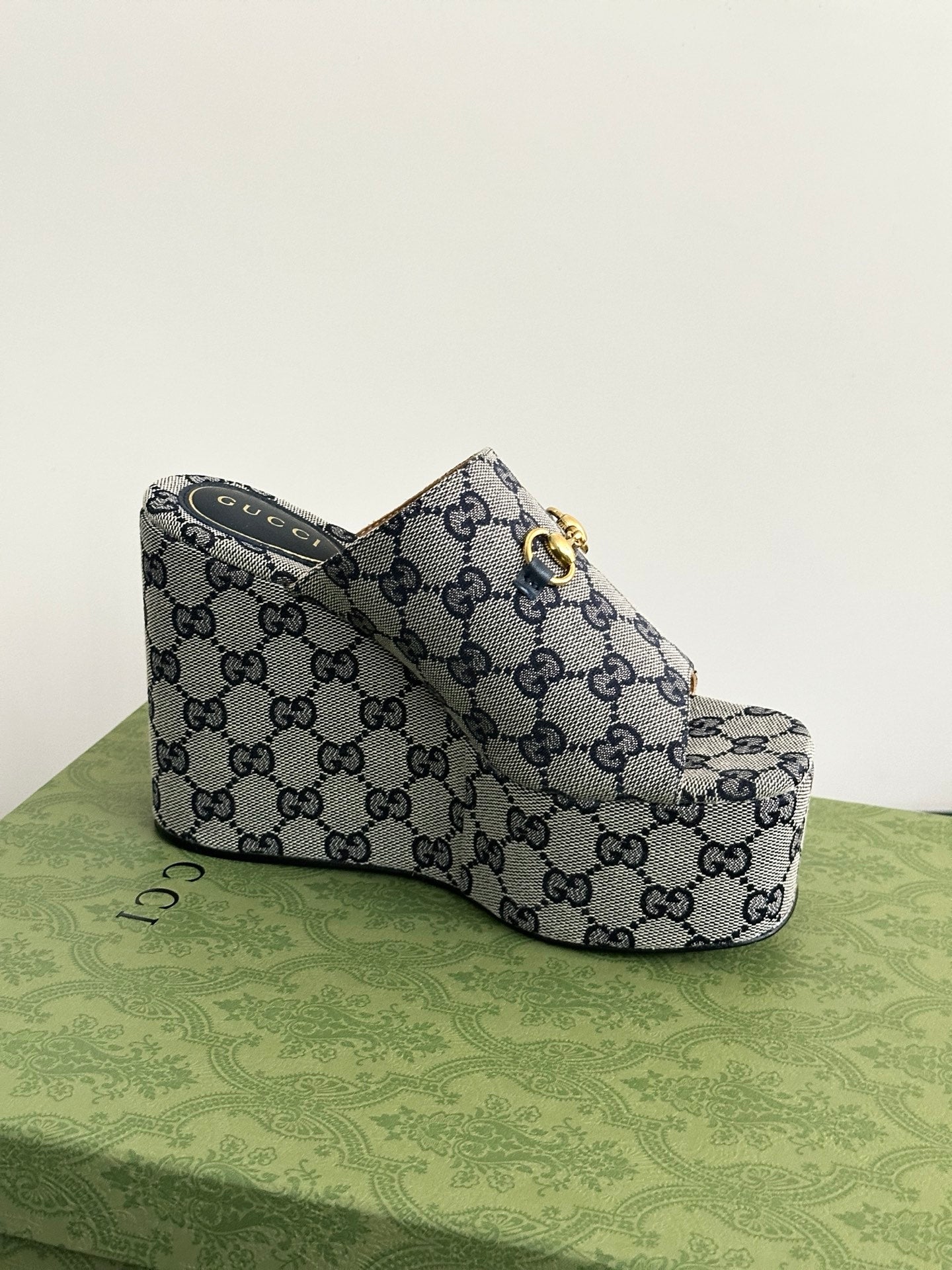Gucci GG-print platform slide sandal with gold-tone buckle detail, side view.