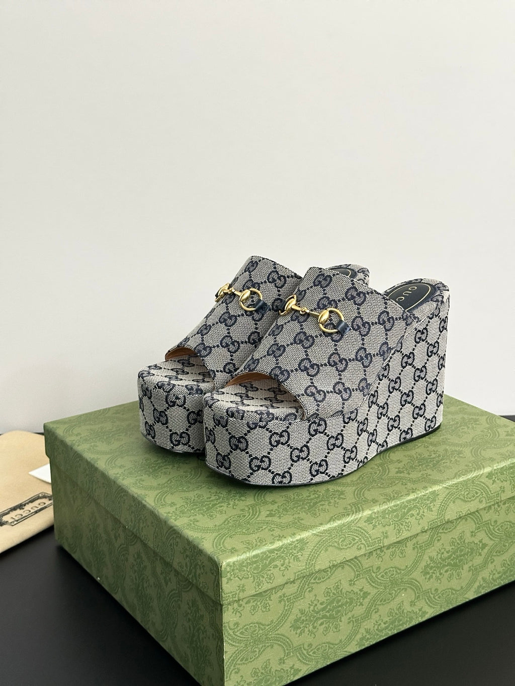Gucci GG-print platform slide sandals with gold-tone buckle strap and open toe.