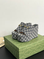 Gucci GG-print platform slide sandals with gold-tone buckle strap and open toe.