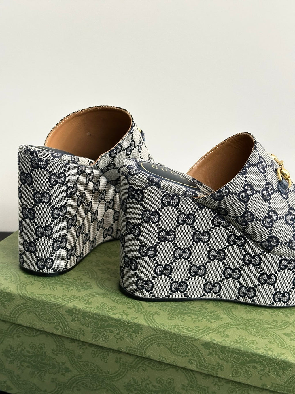 Gucci GG-print platform slide sandals with tan lining and gold buckle hardware, side view.