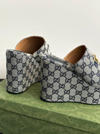 Gucci GG-print platform slide sandals with tan lining and gold buckle hardware, side view.