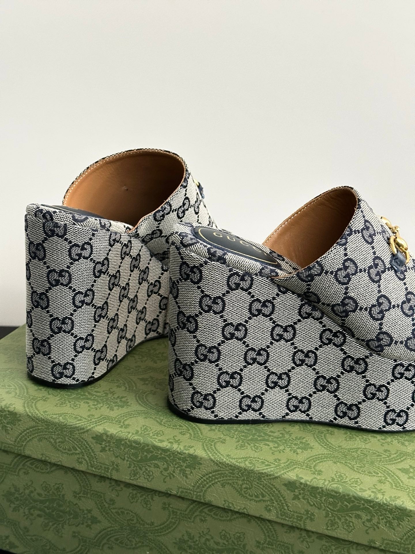 Gucci GG-print platform slide sandals with tan lining and gold buckle hardware, side view.