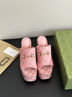 Pink Gucci platform slide sandals with GG logo canvas and gold buckle detail.